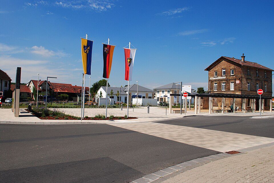 Wärmepumpe-Gurus in Flörsheim-Dalsheim – Bahnhofsvorplatz und Bahnhofsgebäude (Foto: Timonsheim) Bahnhofsvorplatz und Bahnhofsgebäude in Flörsheim-Dalsheim – Wärmepumpe-Gurus vermittelt Fachbetriebe in Flörsheim-Dalsheim